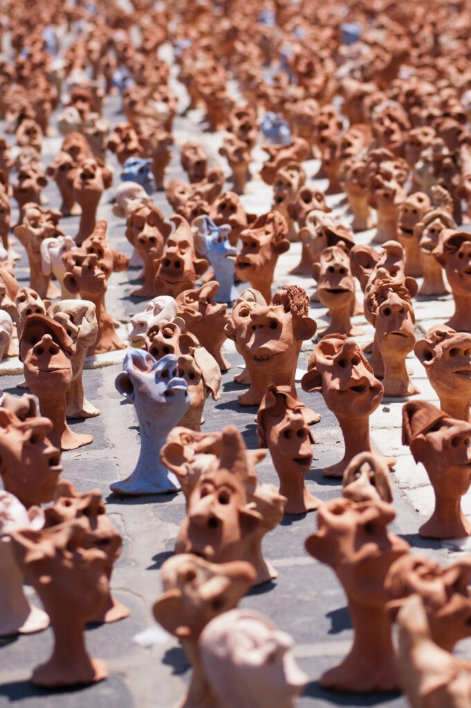 Multiple small clay heads on a sidewalk
