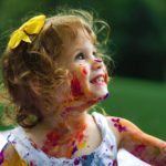 Paint-covered smiling girl