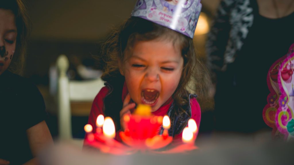 Girl blowing out candles on a birthday cake