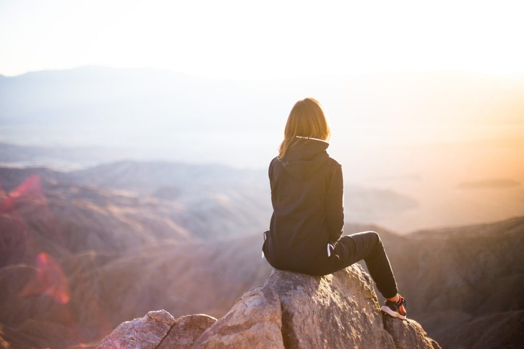 Woman sitting alone on the top of a mountain.
